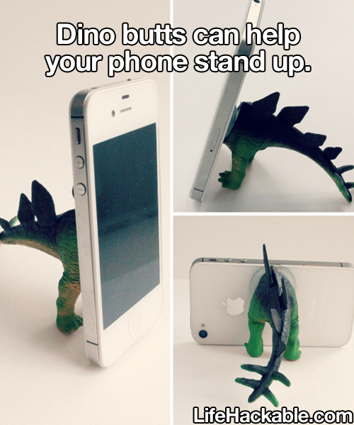 Image: A mobile phone propped up by the posterior half of a bisected toy Stegosaurus. Image text: Dino butts can help your phone stand up.